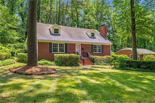 a brick house with a big yard and large trees