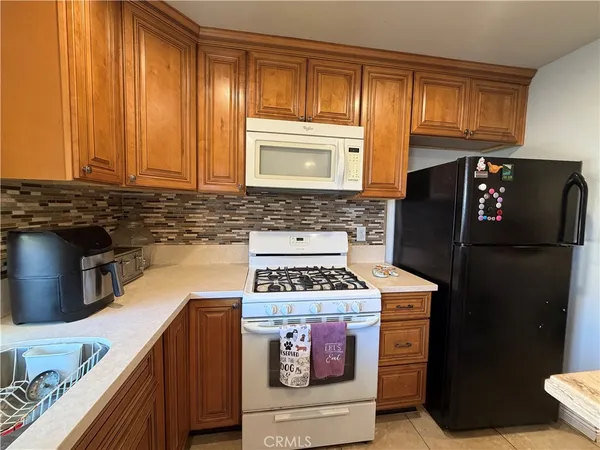 a kitchen with granite countertop a stove a refrigerator and cabinets