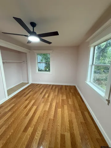 a view of empty room with wooden floor and fan
