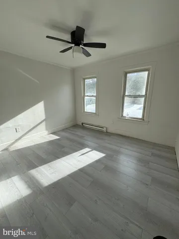 a view of empty room with wooden floor and fan
