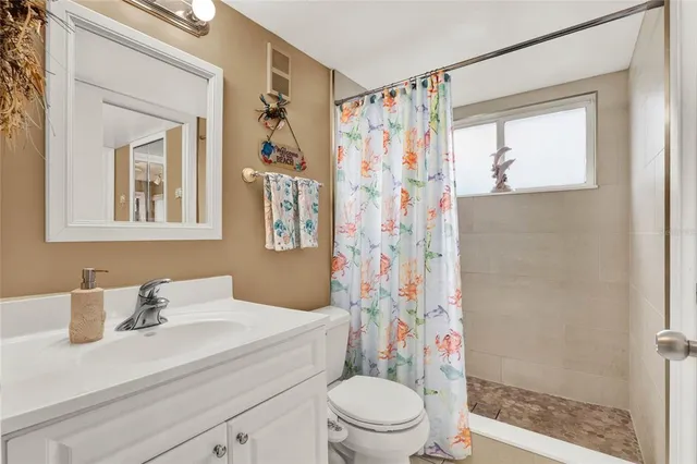 a view of a hallway with wooden floor and a bathroom