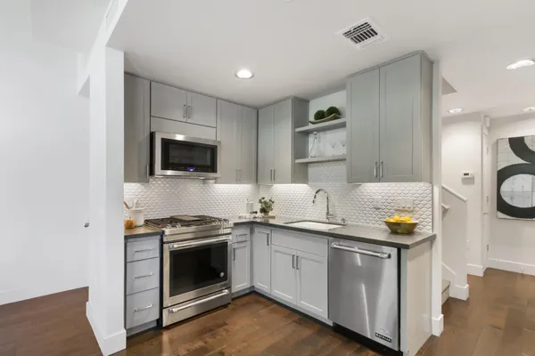 a kitchen with a sink and a stove top oven with wooden floor