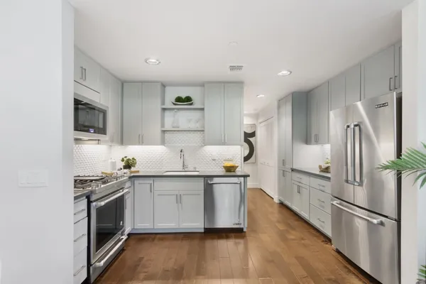a kitchen with stainless steel appliances a sink a stove a refrigerator cabinets and a oven