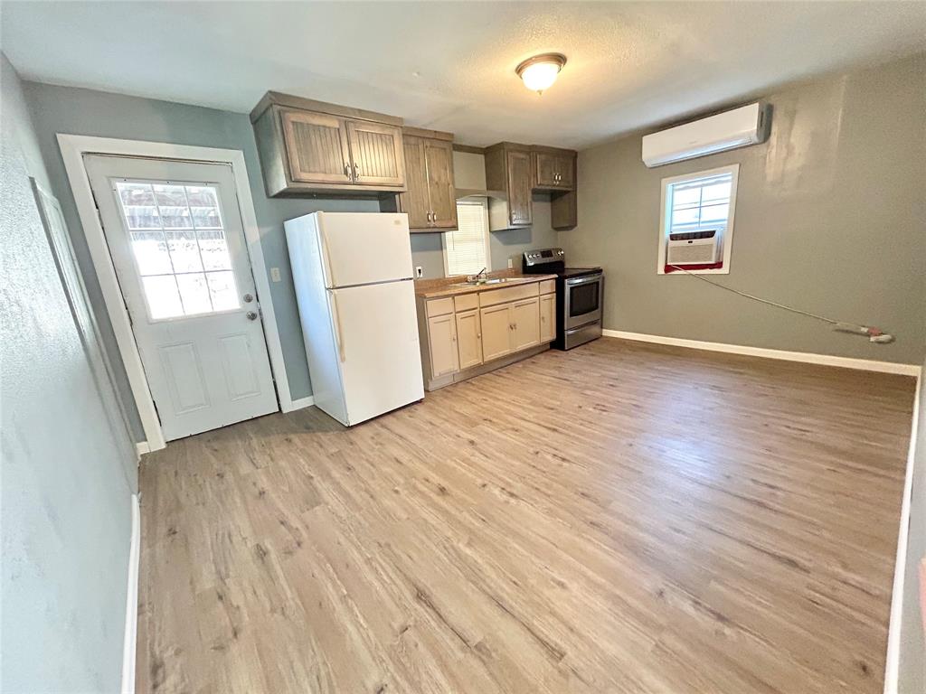 602 Ella Street Dublin, TX 76446 - Photo 7 of 13 a view of a kitchen with wooden floor and a refrigerator
