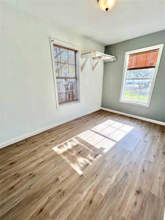 602 Ella Street Dublin, TX 76446 - Photo 8 of 13 an empty room with wooden floor cabinet and windows