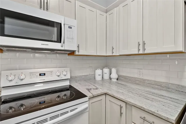 a kitchen with granite countertop a stove and white cabinets