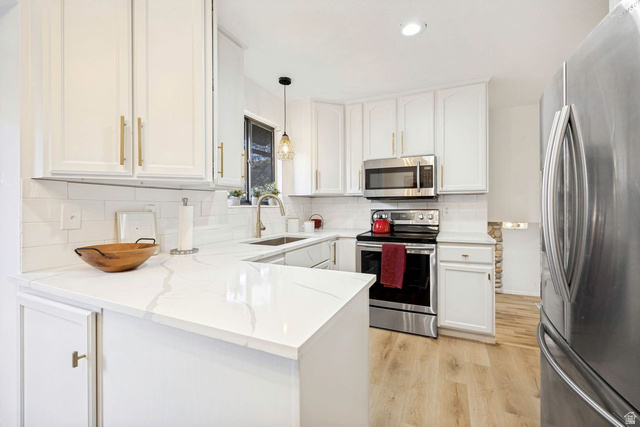 1723 Albury Road Sandy, UT 84092 - Photo 2 of 23 Kitchen featuring white shaker cabinetry with gold-tone hardware, white subway tile backsplash, and light wood-finish flooring