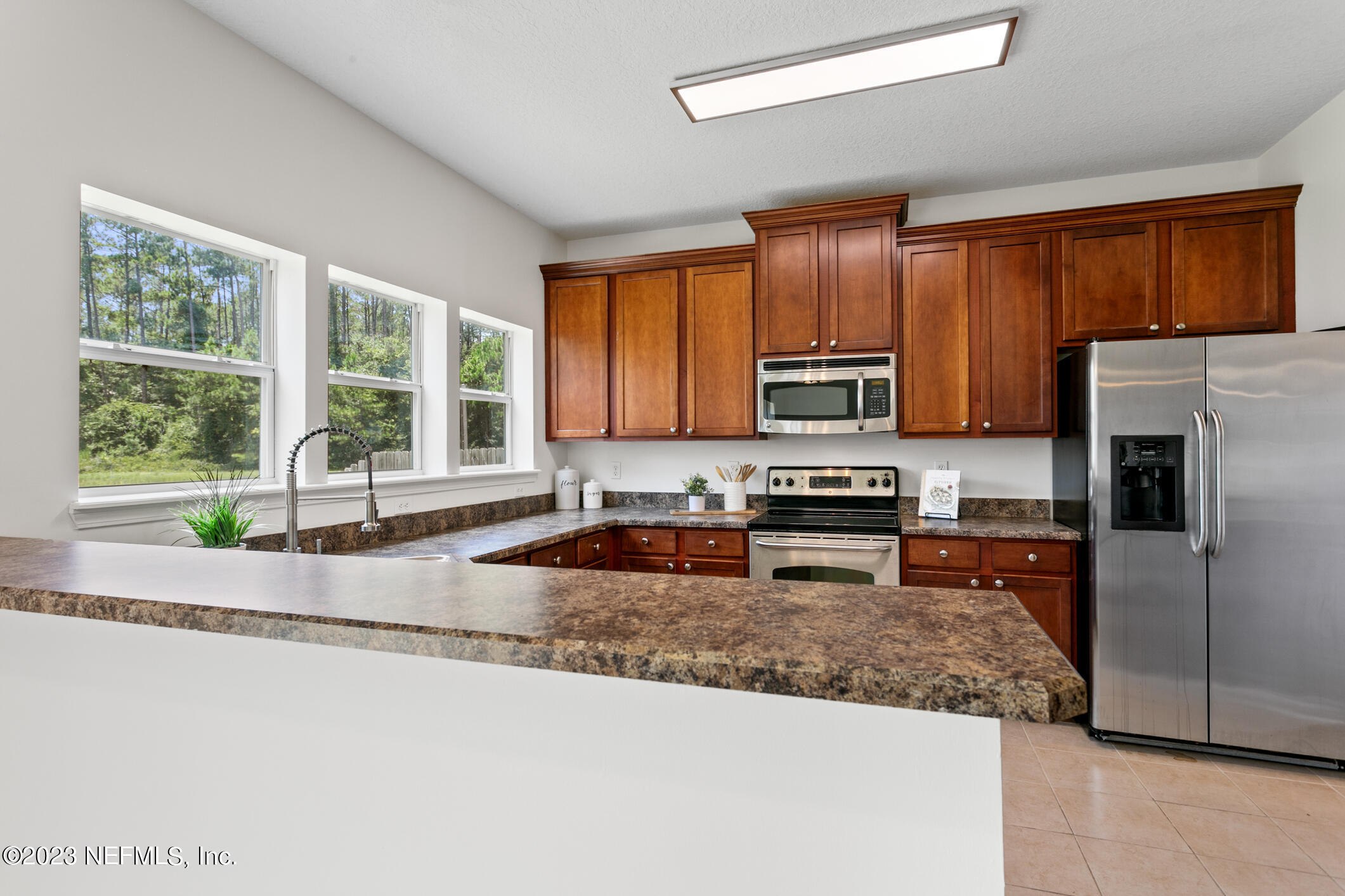 9188 Raptor Drive Jacksonville, FL 32221 - Photo 13 of 36 a kitchen with granite countertop wooden cabinets a refrigerator and a sink