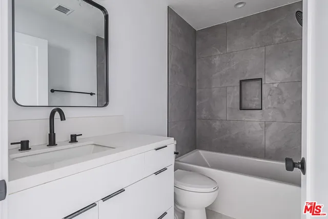 a bathroom with a toilet a sink a mirror and vanity