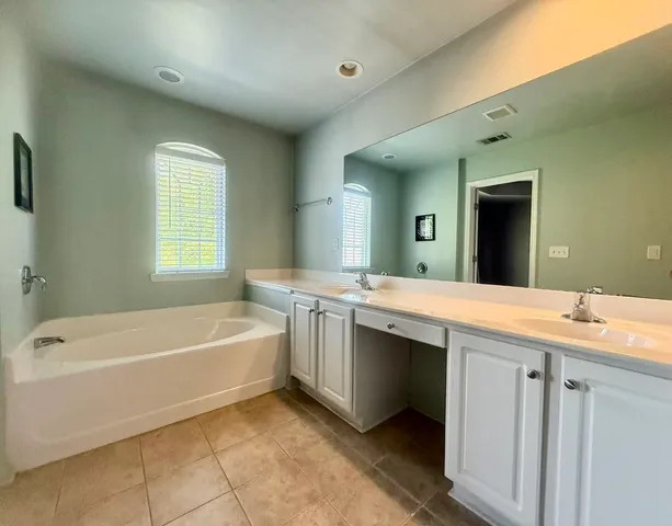 a spacious bathroom with a tub sink shower and mirror