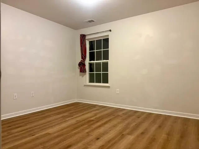 a view of an empty room with wooden floor and windows