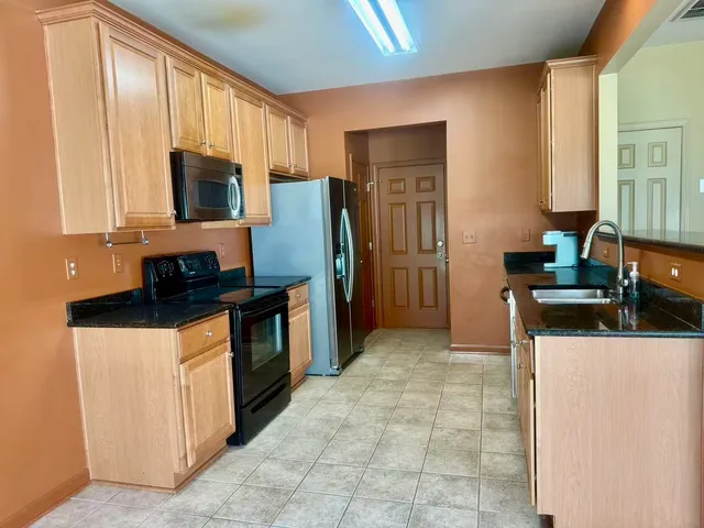 a kitchen with stainless steel appliances granite countertop a refrigerator stove top oven and sink