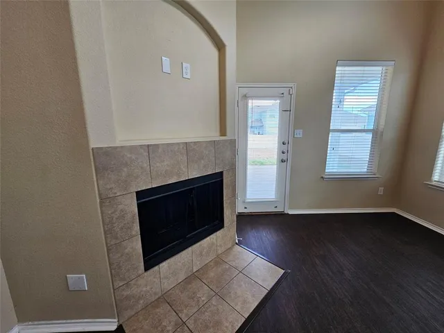 an empty room with wooden floor fireplace and windows