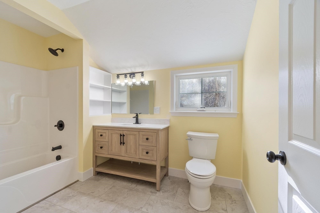 120 Townsend Street, Unit 1 Pepperell, MA 01463 - Photo 17 of 25 a bathroom with a toilet a sink a mirror a bathtub and shower