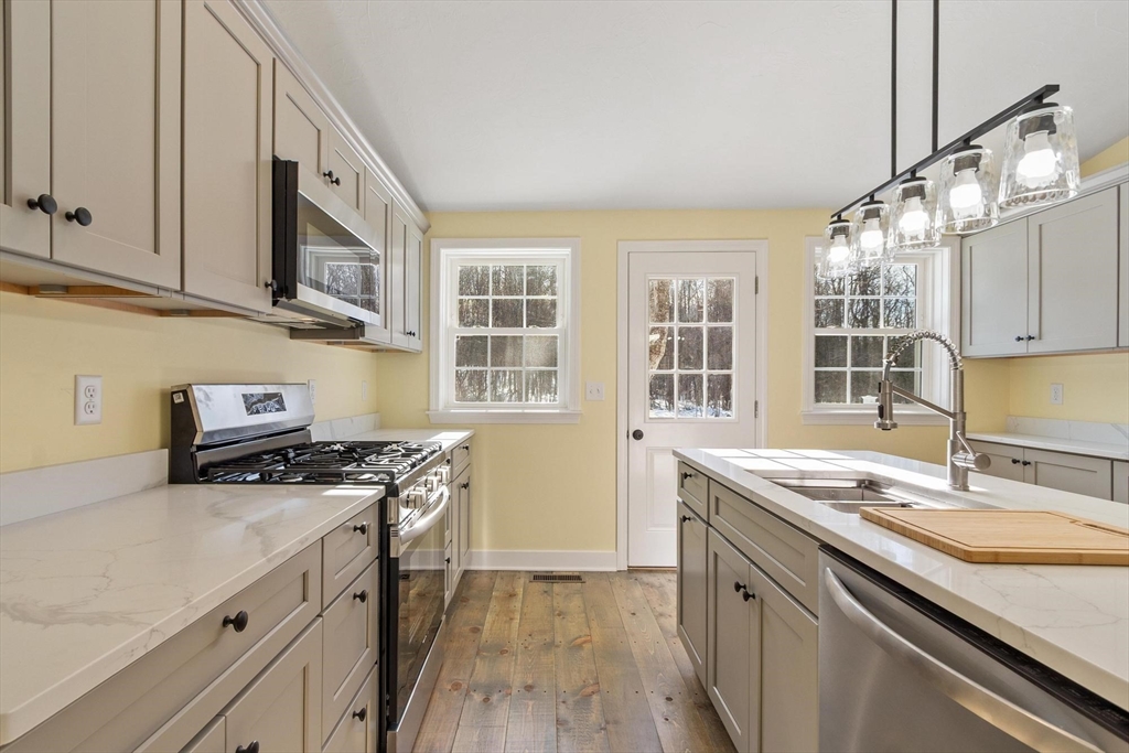 120 Townsend Street, Unit 1 Pepperell, MA 01463 - Photo 3 of 25 a kitchen with stainless steel appliances granite countertop a sink stove and cabinets