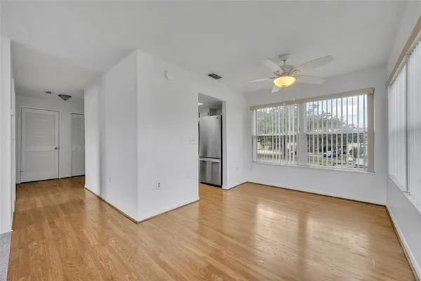 a view of an empty room with a window and wooden floor