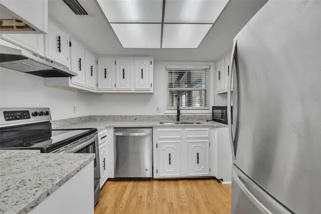a kitchen with stainless steel appliances granite countertop a stove a sink and a refrigerator