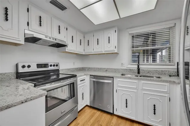 a kitchen with cabinets appliances a sink and a window