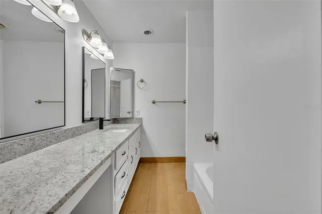 a bathroom with a granite countertop sink a vanity and shower