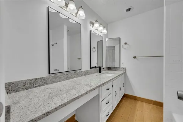 a bathroom with a granite countertop sink a mirror and a shower