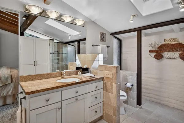 a bathroom with a granite countertop sink a toilet and a mirror