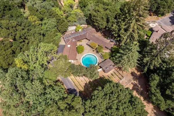 an aerial view of a house with a yard and trees all around