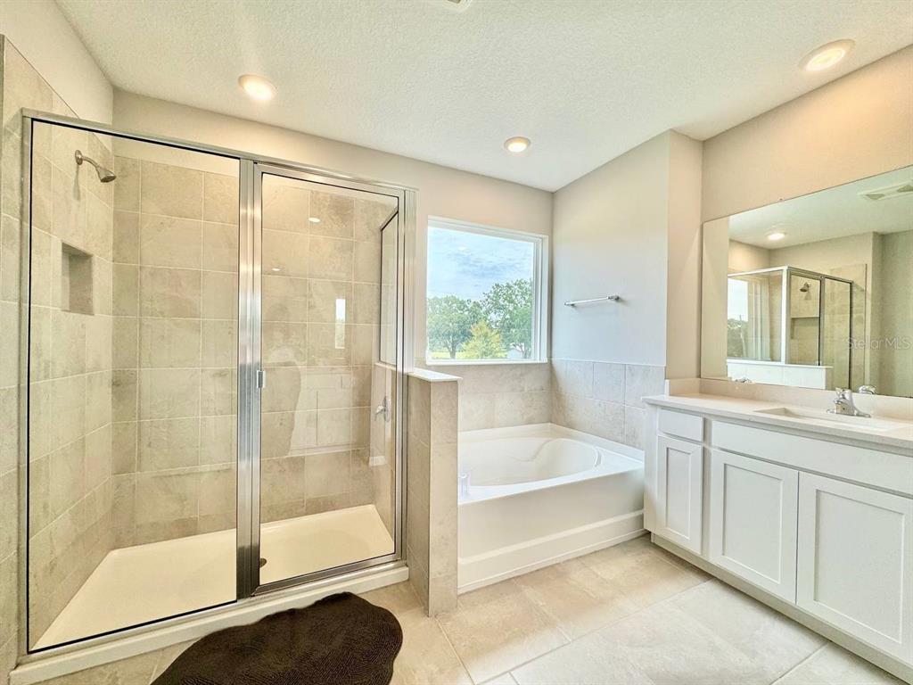 7724 Broad River Avenue Land O Lakes, FL 34638 - Photo 33 of 40 a spacious bathroom with a glass shower door and a bathtub
