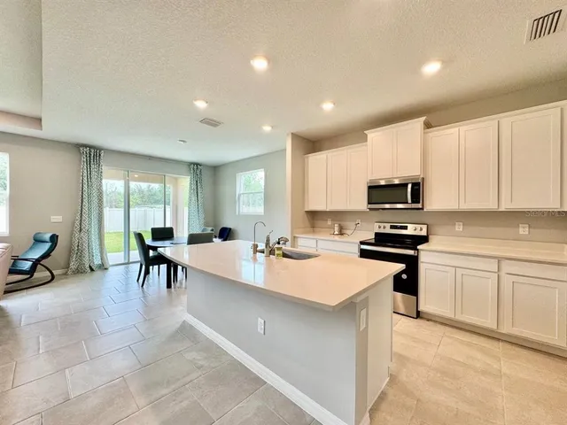 a large white kitchen with stainless steel appliances lots of counter space and breakfast area