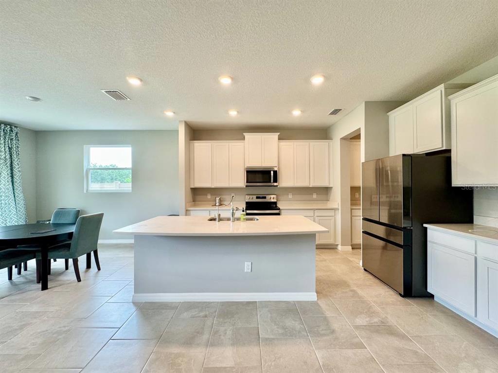 7724 Broad River Avenue Land O Lakes, FL 34638 - Photo 6 of 40 a large kitchen with kitchen island a sink a stove a dining table and chairs