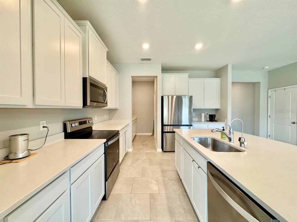 7724 Broad River Avenue Land O Lakes, FL 34638 - Photo 9 of 40 a kitchen with stainless steel appliances granite countertop a sink and a refrigerator