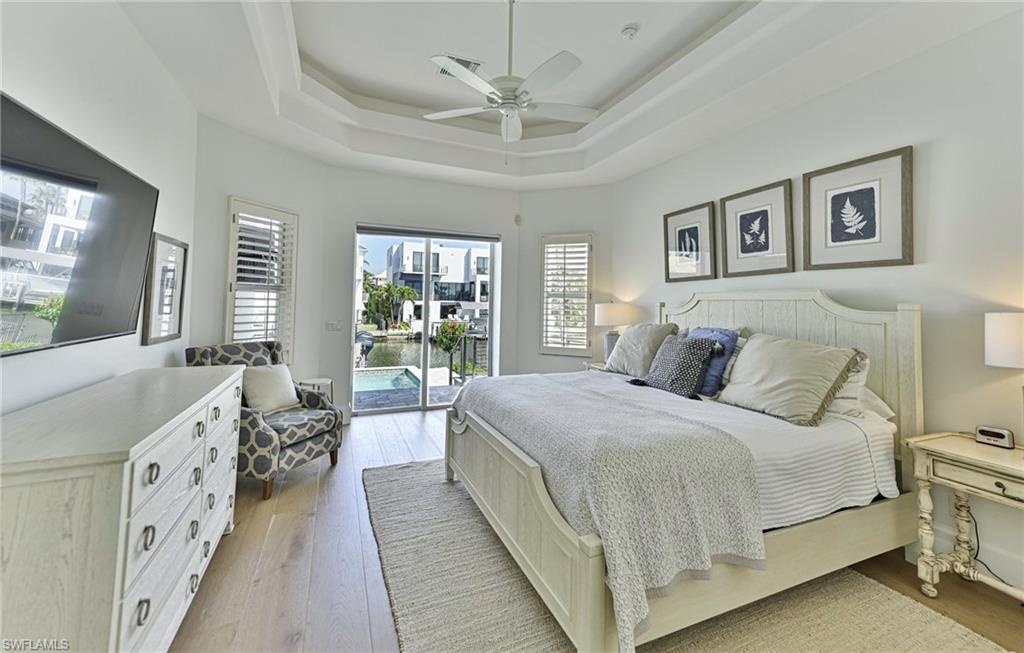 271 Bayview Avenue Naples, FL 34108 - Photo 18 of 35 a spacious bedroom with a large bed and a chandelier fan
