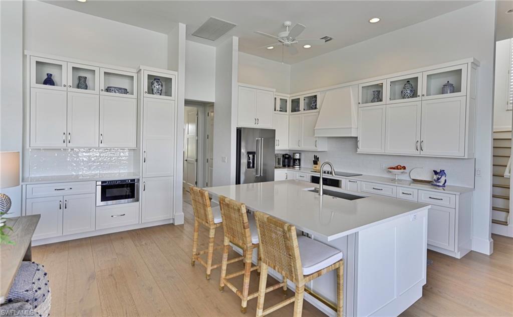 271 Bayview Avenue Naples, FL 34108 - Photo 7 of 35 a kitchen with white cabinets and stainless steel appliances