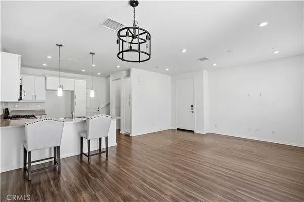 a view of dining room kitchen with stainless steel appliances wooden floor dining table and chairs