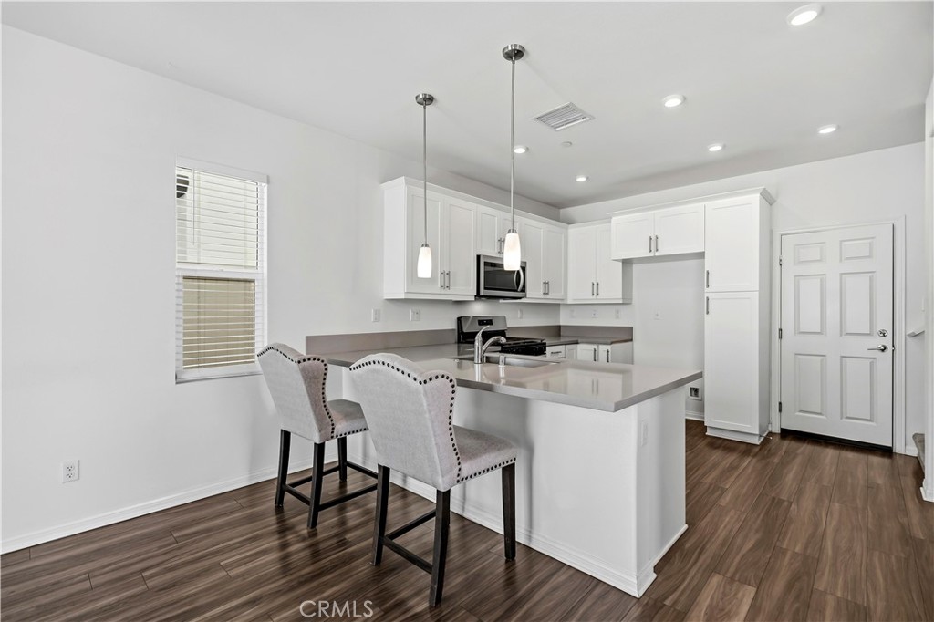 335 Carson Court Rialto, CA 92376 - Photo 5 of 34 a kitchen with stainless steel appliances granite countertop a refrigerator a sink dishwasher a stove and white cabinets with wooden floor