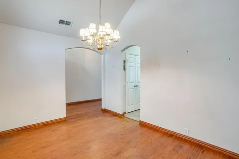 a view of an empty room with chandelier fan