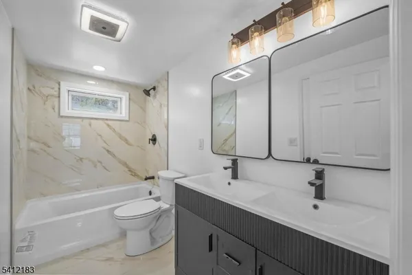 a bathroom with a bathtub shower sink vanity mirror and toilet