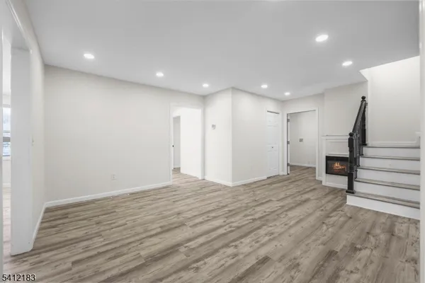 a view of an empty room with wooden floor and stairs