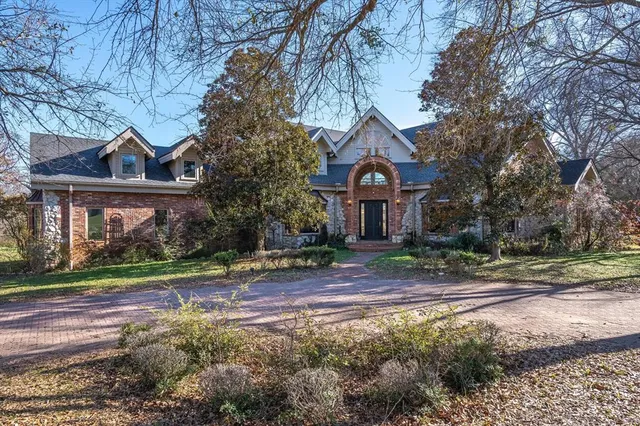 a front view of a house with a yard and large trees