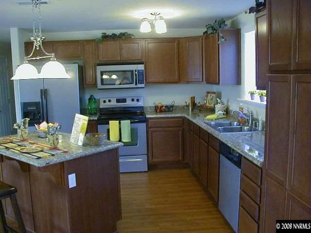 16035 Tourmaline Drive Reno, NV 89521 - Photo 5 of 9 a kitchen with kitchen island granite countertop a sink stove and cabinets