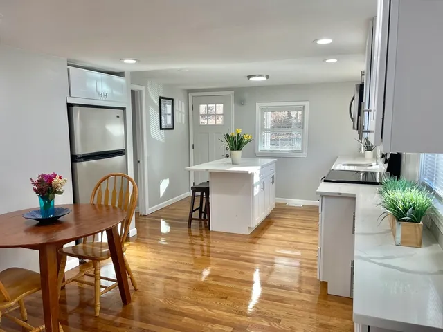a living room with furniture potted plant and open kitchen view