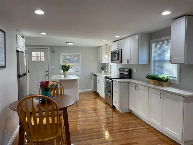a kitchen with white cabinets stainless steel appliances and dining table