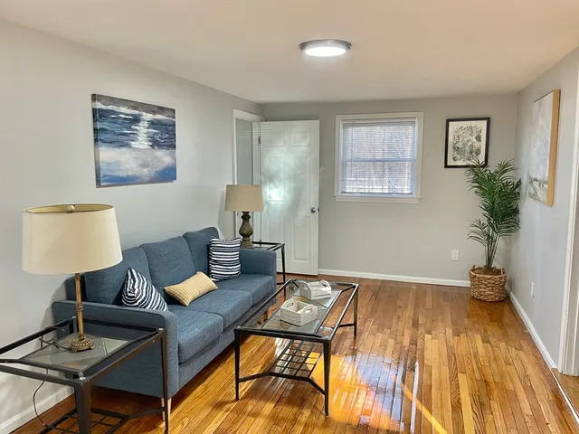 a living room with a couch and a lamp on table with wooden floor