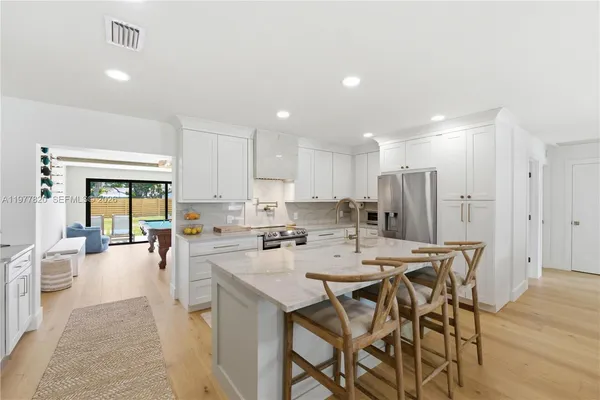 a kitchen with a dining table chairs wooden floor appliances and cabinets