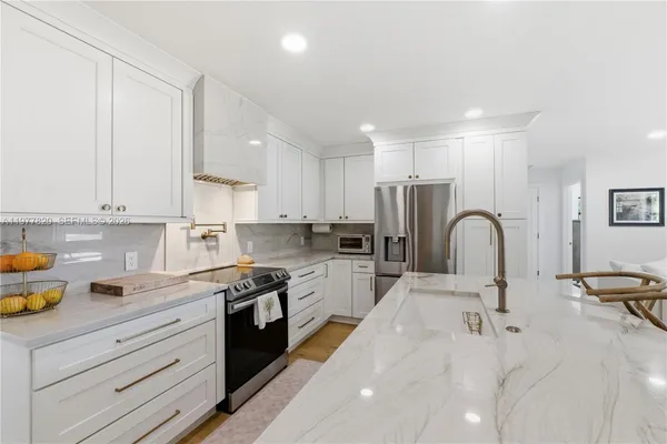 a kitchen with a sink white cabinets and stainless steel appliances