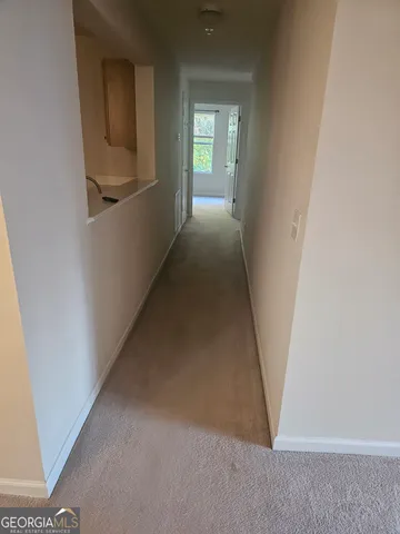 a view of a hallway to a bedroom with wooden floor and a window