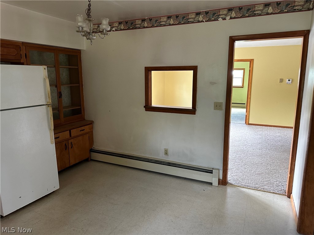 2288 Martin Road Mogadore, OH 44260 - Photo 5 of 27 Unfurnished dining area with baseboard heating, an inviting chandelier, and light colored carpet