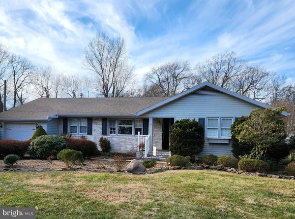a front view of house with yard and trees in the background