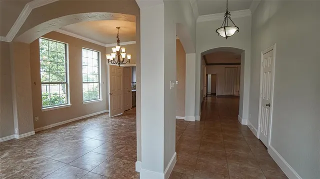 a view of a hallway with chandelier and glass door