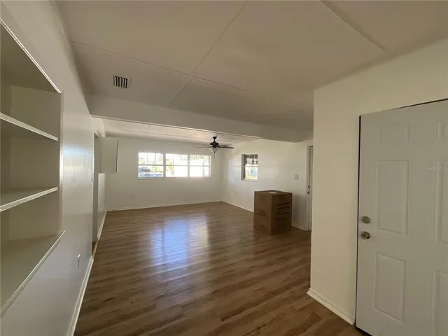 a view of empty room with wooden floor and fan