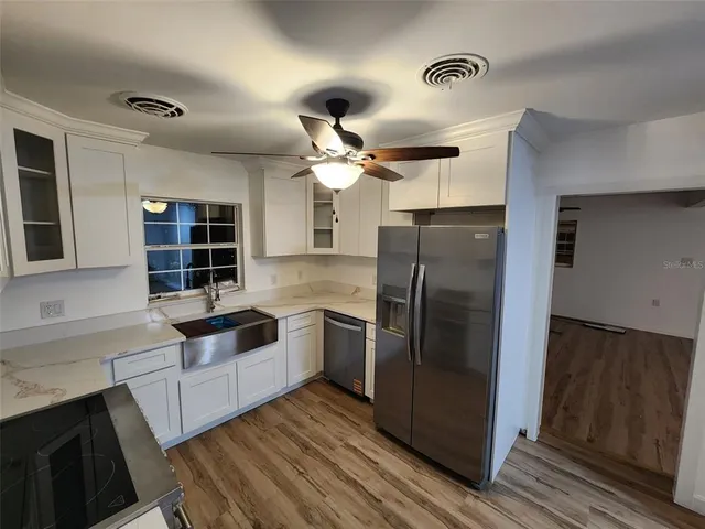 a kitchen with a sink and white cabinets with wooden floor